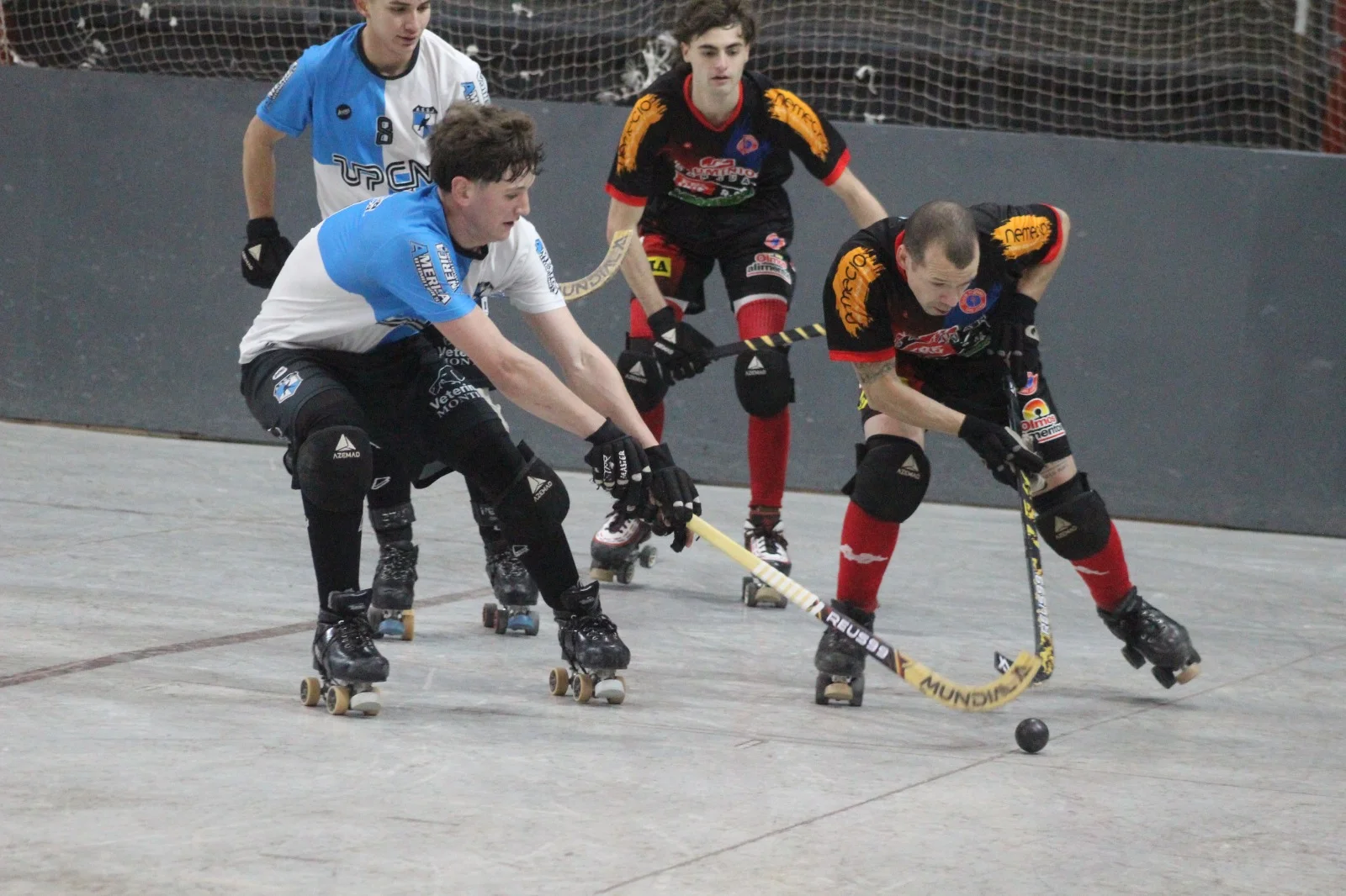 Jugadores compitiendo en hockey sobre patines con movimiento dinámico y público en las tribunas